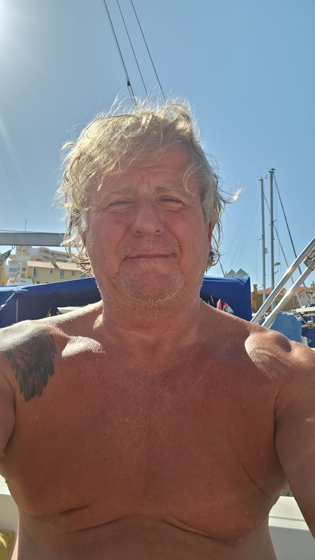 A man with his shirt off in a boat yard